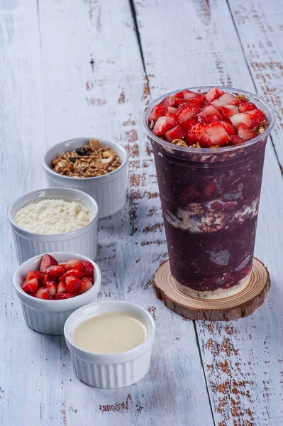 Plastik bardakta donmuş acai, meyve ve mezeler, granola, süt tozu, çilek ve konsantre süt. Boşluğu Kopyala