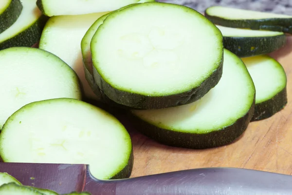 Zucchini in Scheiben geschnitten auf einem Holzbrett — Stockfoto