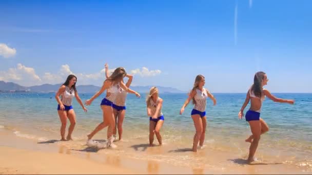 Söta cheerleaders på grunt vatten på stranden — Stockvideo
