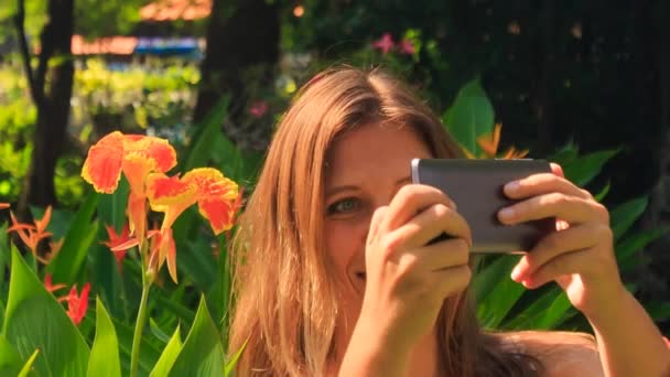 Chica hace selfie contra flores tropicales — Vídeo de stock