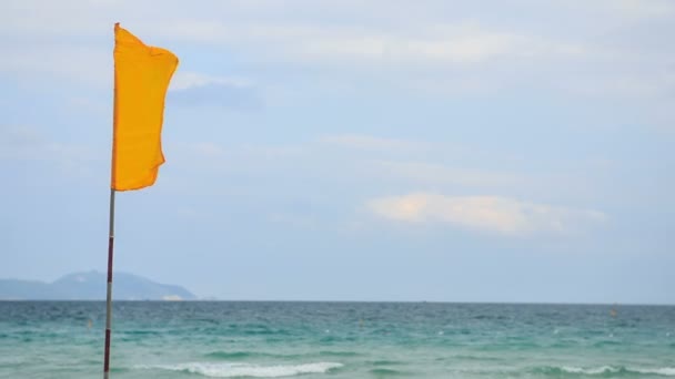 Flaps de vento bandeira amarela contra o mar — Vídeo de Stock