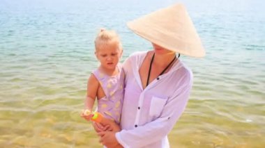 Annesi Vietnamlı şapkalı kızı tutar