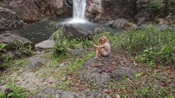 Malá holka sedí na kameni — Stock video