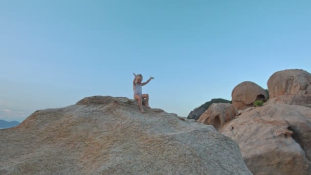 Little girl climbs up large bare rock — Stock Video