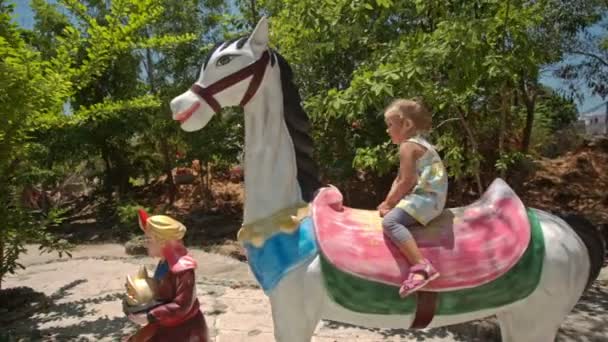 Little girl sits on horse model statue — Stock Video