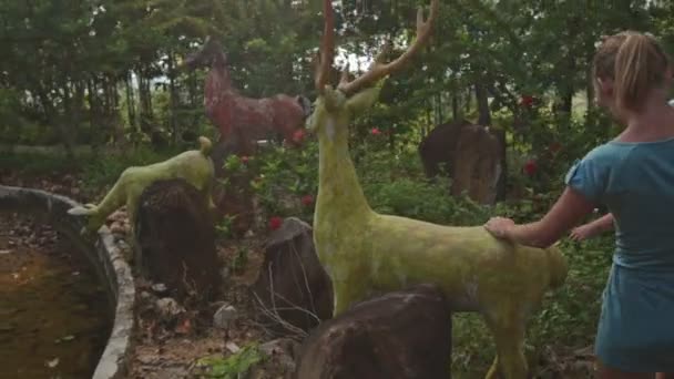 Ragazza sale su scultura di cervo di pietra — Video Stock