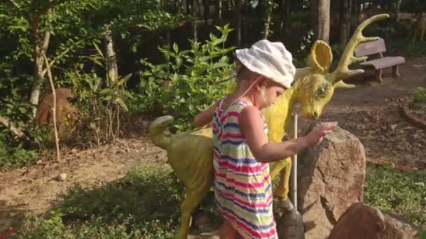 Fille grimpe sur la sculpture de cerf — Video