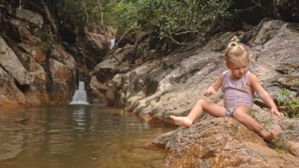 Mała dziewczynka siedzi na kamieniu — Wideo stockowe