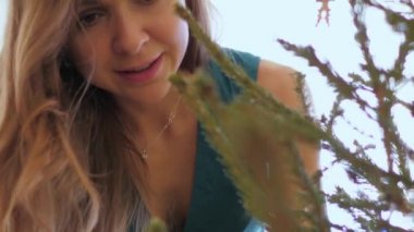 Genç bir kadın Noel ağacına oyuncak asmak için eğiliyor