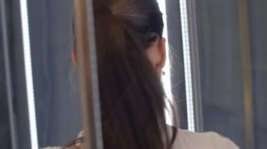 At kuyruklu genç kadın duş kabinine yakından bakıyor.