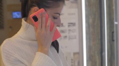 Genç kadın elinde renkli bir akıllı telefon tutuyor ve kocasıyla konuşuyor.