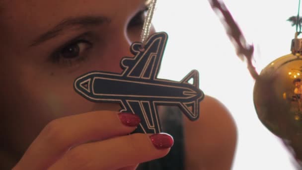 숙련 된 여자가 새해 나무에서 비행기 모양의 장난감을 보고 있다 — 비디오