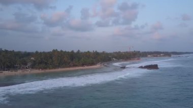 Kumlu sahil şeridi ve köpüklü okyanus dalgaları kumsalda yuvarlanıyor.