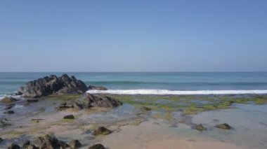 Beyaz köpüklü sonsuz okyanus dalgaları kumlu sahilde yuvarlanıyor.