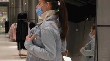 Mavi tek kullanımlık maskeli genç kadın ceketini çıkarıyor.