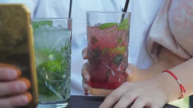 Kadın kadehi kokteylle tutar ve erkek selfie çeker.