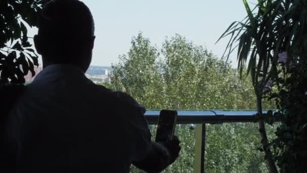 Man houdt telefoon in uitgestrekte hand op cafe terras — Stockvideo