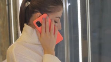 Bayan akıllı telefondan konuşuyor ve büyük bir hırdavatçıda geziniyor.