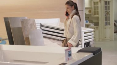 Siyah akıllı telefonlu genç bir kadın siparişçiyle konuşuyor.