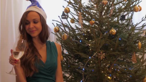 Noel şapkalı kadın şampanya bardağıyla oturur. — Stok video