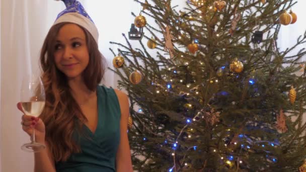 Dame au chapeau x-mas s'assoit avec verre à vin champagne par sapin — Video