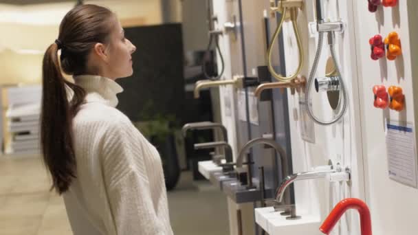 Young woman in ponytail chooses tap standing at set — Stock Video