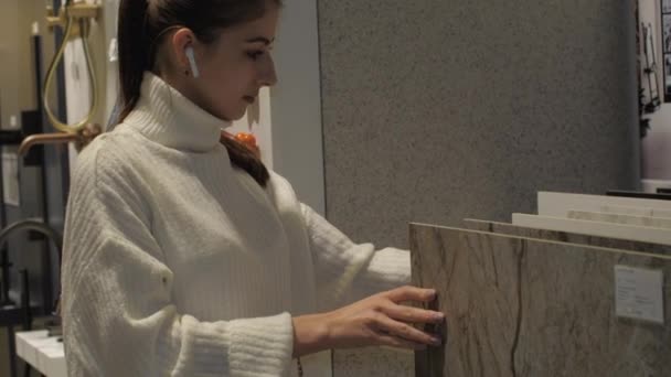 Młoda kobieta z białymi słuchawkami bezprzewodowymi wybiera płytkę — Wideo stockowe