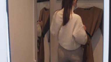 Genç kadın kahverengi elbiseden siyah deri kemer alıyor.