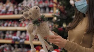 Genç kadın hediye seçmek için kahverengi geyik oyuncağına dokunuyor.