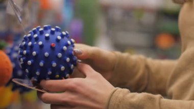 Profesyonel alışveriş yapan eller çivili mavi köpek topuna dokunur.