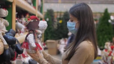 Tek kullanımlık maske takan kadın yumuşak elf oyuncağı tutuyor.
