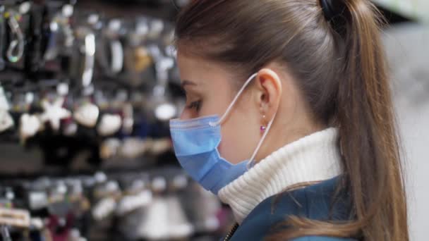 Lady in mask looks at hairpins standing at wide range — Stock Video