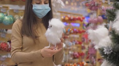 Kadın kabarık kuş heykelciğine bakar ve yeşil çam ağacı takar.