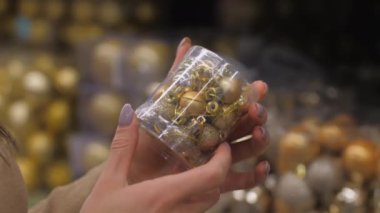 Elleri parlak sarı mücevherlerle dolu plastik kapları tutuyor.