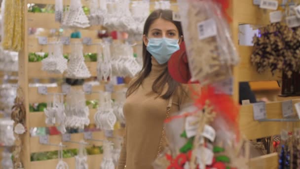 Young woman in face mask walks along store and looks around — Stock Video