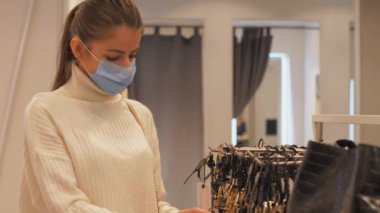 Mavi maskeli genç kadın aksesuarlara bakıyor.