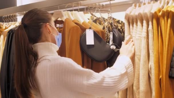 Zkušený nakupující v masce se dotýká bílého bavlněného svetru — Stock video