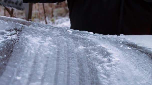Osoba trzyma skrobak lodu i czyści przednią szybę pojazdu — Wideo stockowe