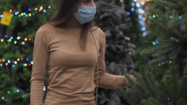 Tasarımcı mağazadaki yapay Noel ağaçları arasında geziniyor