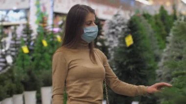 Genç bir kadın yeşil çam ağacına yaklaşıyor.