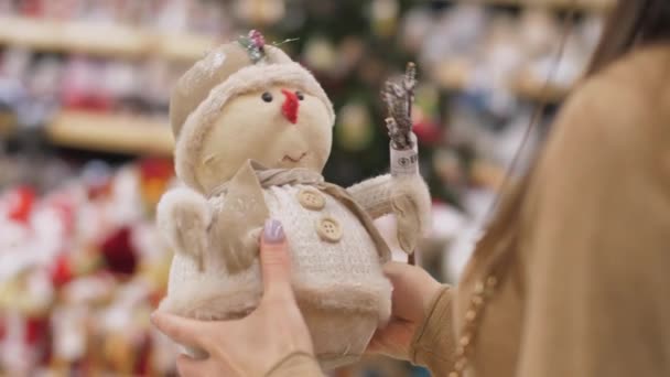 Νεαρή γυναίκα χέρια αγγίζουν χειροποίητα παιχνίδι χιονάνθρωπος στο κατάστημα — Αρχείο Βίντεο