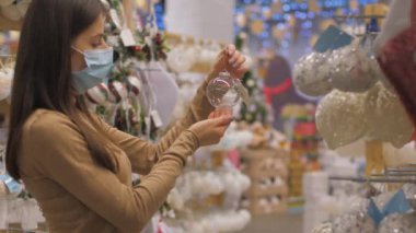 Yüz maskesi takan profesyonel alışverişçinin elinde şeffaf bir mücevher var.