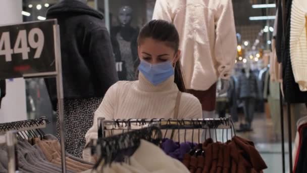 Lady in face mask se aleja de la colección de pullovers — Vídeo de stock