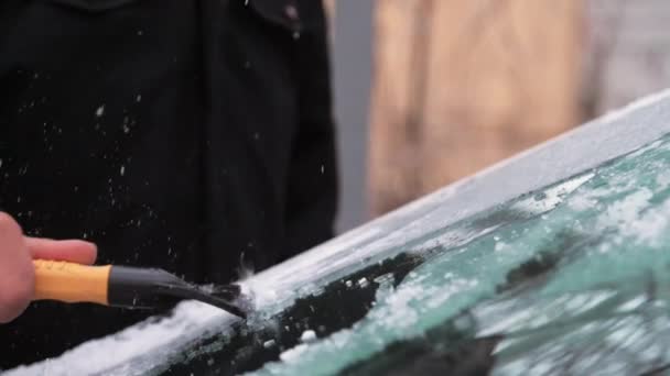 Рука человека очищает лобовое стекло от сосульки — стоковое видео