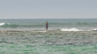 Ağ ile Asyalı balıkçılar okyanus dalgalarında duruyorlar.