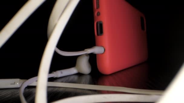Téléphone avec écouteurs filaires et sans fil sur table noire — Video