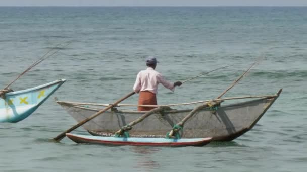 Азиатский мужчина ловит рыбу со стержнем в лодке с балансировщиком в море — стоковое видео