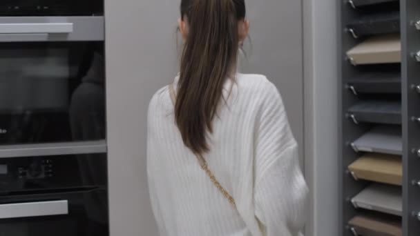 Jovem mulher em pulôver branco se aproxima da geladeira — Vídeo de Stock