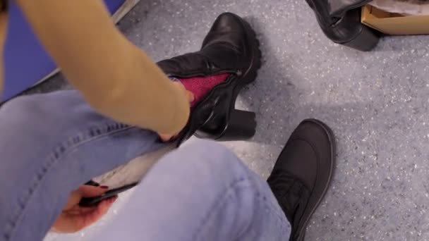 Дама в джинсах пробує чорне зимове взуття в торговому центрі — стокове відео