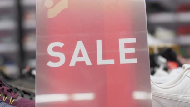 Sale sign of red colour with letters among winter shoes — Stock Video